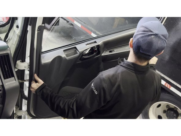 Open the cab door and remove the interior door panel to access the cable routing channel inside the door shell. Start by prying around the panel edges with a trim removal tool, then lift the panel upward to disengage the upper clips before pulling it fully away from the door.
