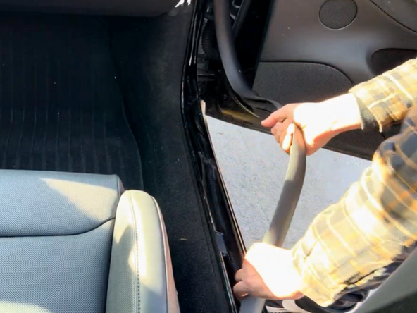 Continue pulling more of the door weather stripping along the bottom of the floorboard.