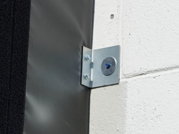 Secure the Side Pad to the building through the mounted angle brackets using anchors, welding, or other best practices based on the building surface.