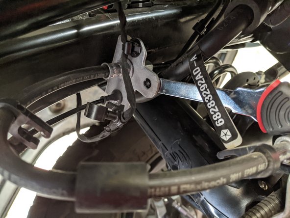 At the frame side bracket where the brake line attaches to the hard line, remove any plastic clips preventing the brake line securing clip from coming off.