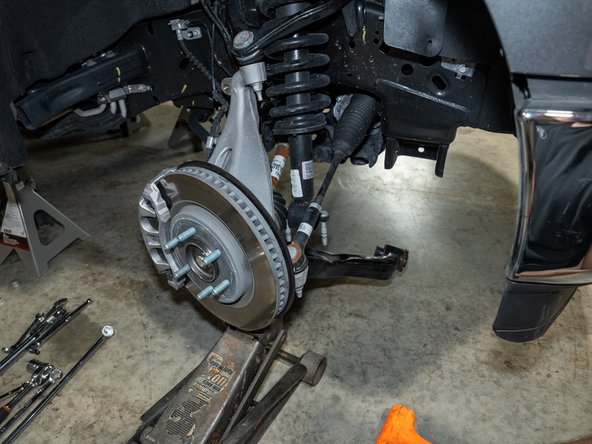 Drop the lower control arm out of its frame brackets and pull the strut out of the vehicle.