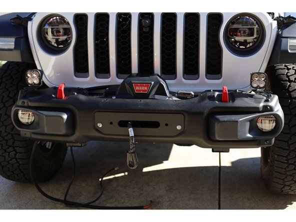 If the winch rope/cable has been installed on the winch drum, place the bumper close to the front of the vehicle and thread the rope/cable through the hole in the front bumper before installing the bumper.