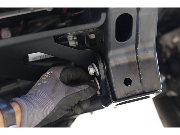 Insert the factory skid plate mounting plate in between the frame and the Winch Plate and thread the provided M10x1.5 x 35mm bolts through both holes. Repeat on the other side of the frame.