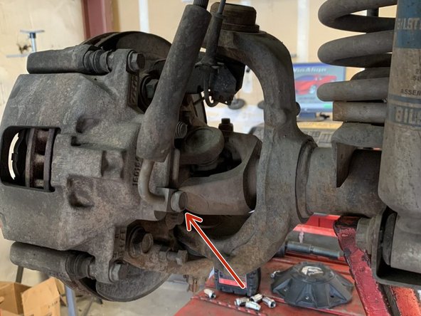 Remove the banjo bolt at the brake caliper with a 15mm wrench/socket. As soon as the bolt is loosened fluid will start leaking. Make sure to have a drain pan ready before loosening the bolt.