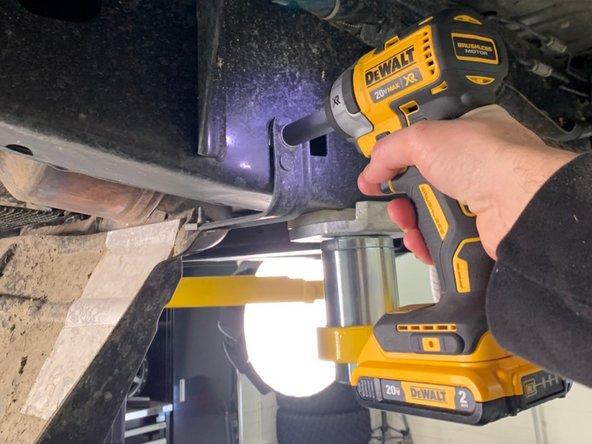 Using a 15mm wrench/socket, remove the two bolts holding the metal support bracket to the crossmember.