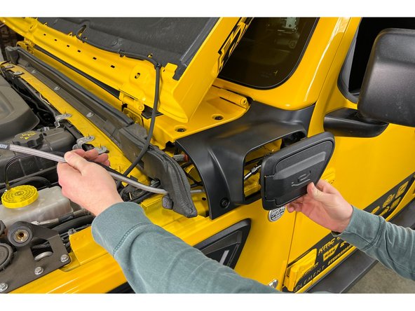 Route the wire harness and air hose from the Charge Port Housing Assembly through the Cowl Trim Panel and into the engine bay.