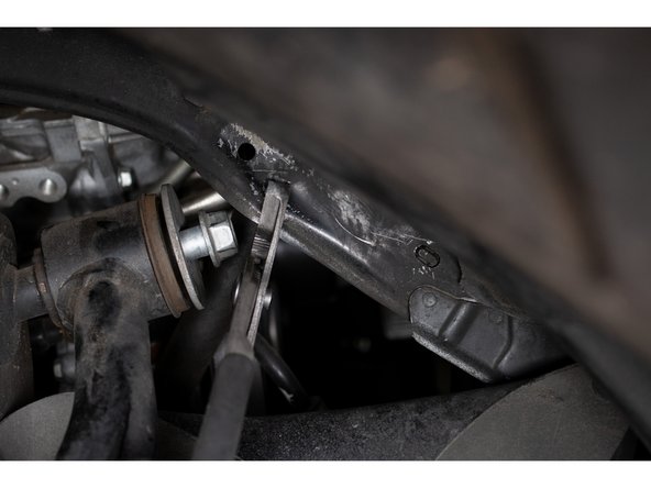 It will be necessary to bend the body sheet metal slightly in order to remove the bolt. A pair of channel locks or a crescent wrench will help accomplish this. Take your time and work around the wire harness and AC lines behind the body sheet metal.