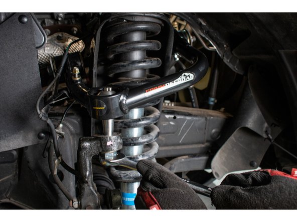 Pivot the tapered stem so that it lines up with the tapered hole in the spindle. Push the upper control arm downward so the tapered pin engages the spindle.