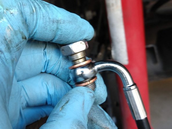 Using a new copper crush washer on each side of the banjo fitting, insert the banjo bolt in the direction of the line as shown.