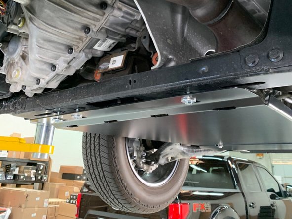 Slide the skid plate over the forward M10 bolts and then install the rear M8 bolts and washers.