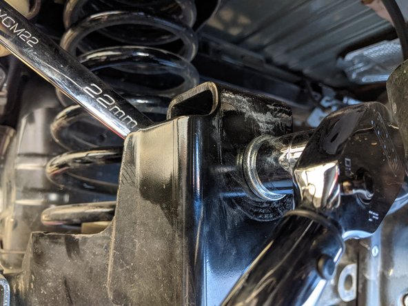 Remove the rear axle side track bar bolt with a 21mm socket/wrench.