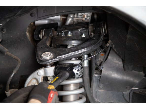 Strike the spindle with a large hammer where the upper ball joint stud engages the spindle. A couple quick strikes should separate the taper. Alternatively, a ball joint separator may be used.