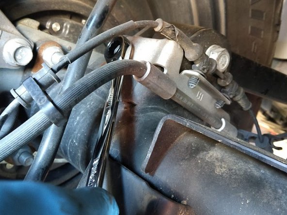 Loosen the axle side retaining bracket with a 13mm wrench.