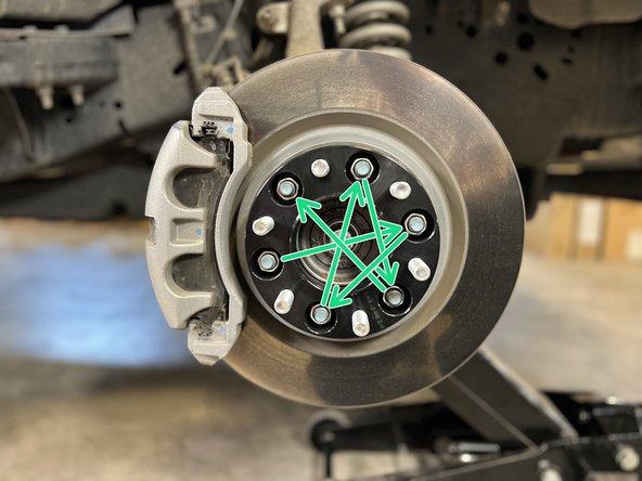Tighten the lug nuts in a star/cross pattern as shown to ensure even tightening. A pry bar can be used to prevent the wheel spacer from spinning.