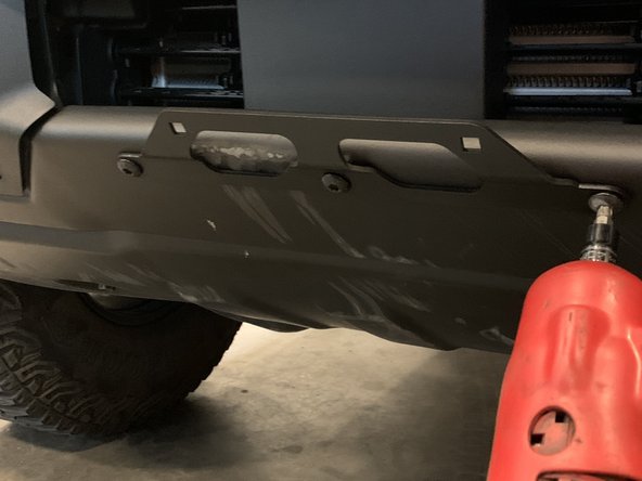 Place mounting bracket against the skid plate and bumper as shown, and re-install the factory hardware.