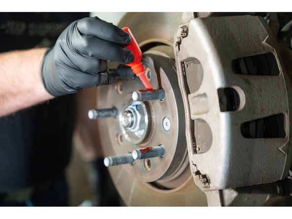 Apply the provided high strength thread locker to the wheel studs on the axle.