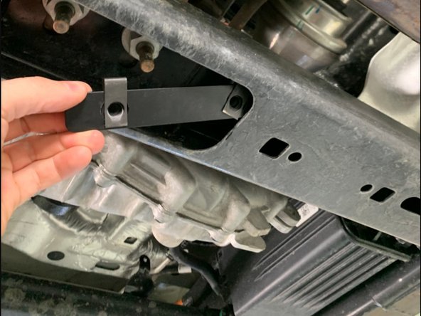 Install the two clip nut tabs into the crossmember just in front of the transfer case and align with the round holes.