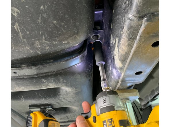 Using a jack to support the front of the fuel tank, remove the front support  strap with a 15mm socket. Rotate the strap 90 degrees in the frame to disengage the other side.