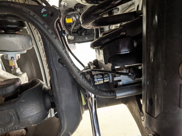 Use a 10mm wrench/socket to unbolt the bracket securing the brake line to the axle.