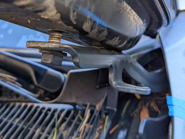 With the mounts loose, feed the bracket with light from the windshield side carefully under the open hood, and slide the bracket in between the bolt heads and the hinge. You may have to squeeze the hood to the hinge with one hand while sliding the bracket in with the other hand.