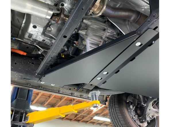 Slide the skid plate over the forward bolts and then install the rear bolts.