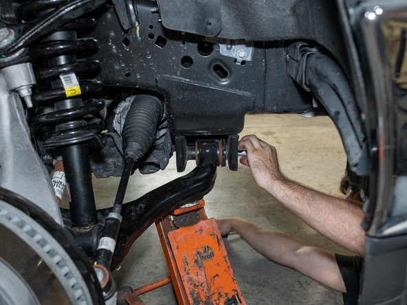 Reconnect lower control arms by using a floor jack to help push the arms into position.