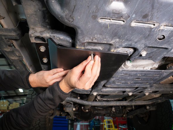 Secure the skid plate with the two frame hex bolts and the included M8 Torx flat head screw.