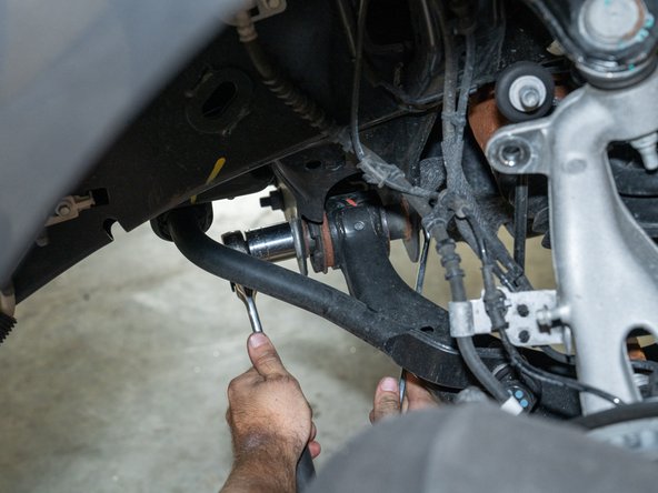 Remove the lower control arm bolts using a 27mm socket/wrench and a 21mm wrench.