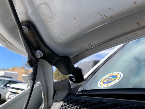 Slide the light bracket onto the hood bolts and then lightly tighten the bolts.