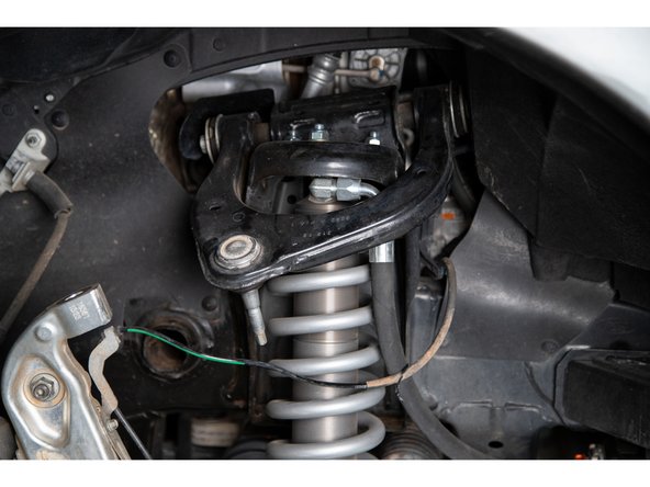 Separate the upper control arm from the spindle and support the spindle so that it does not overextend the CV joints when detached.