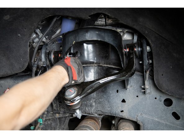With the upper control arm detached from the spindle, begin to loosen the upper control arm from its mounts in the frame using a 21mm socket/wrench.