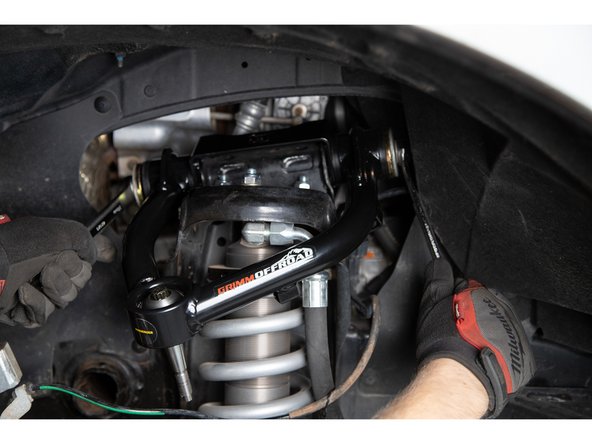 Slide the frame bolt in from the back of the upper control arm. Make sure that the supplied washers are placed on the outside face (outer front and outer rear) of the hat bushings.