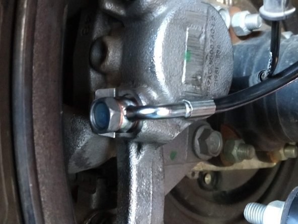 Thread the banjo bolt into the caliper, with the new brake line running along the caliper, towards the front of the vehicle.