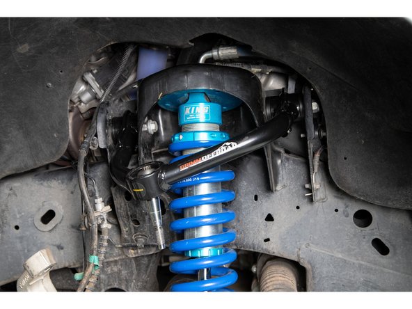 Pivot the tapered stem so that it lines up with the tapered hole in the spindle. Push the upper control arm downward so the tapered pin engages the spindle.