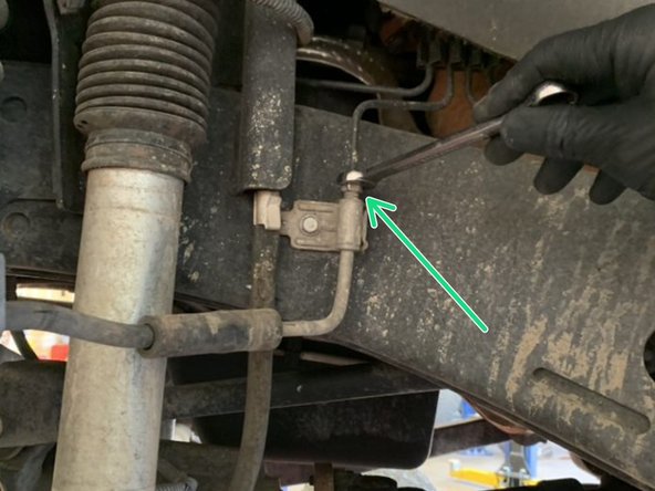 Remove the hard line nut from the factory brake line bracket where it mounts to the frame using a 12mm flare nut wrench. As soon as the nut is loosened, brake fluid will start leaking. Make sure to have a drain pan in place before loosening the nut.