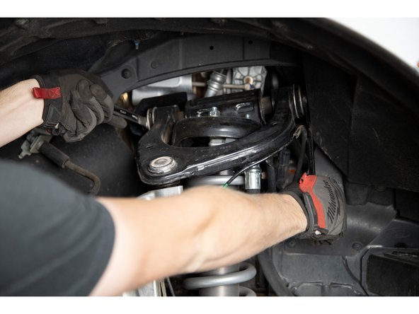 Remove the nut from the pivot bolt using an 18mm socket/wrench on the bolt head and a 21mm socket/wrench on the nut.