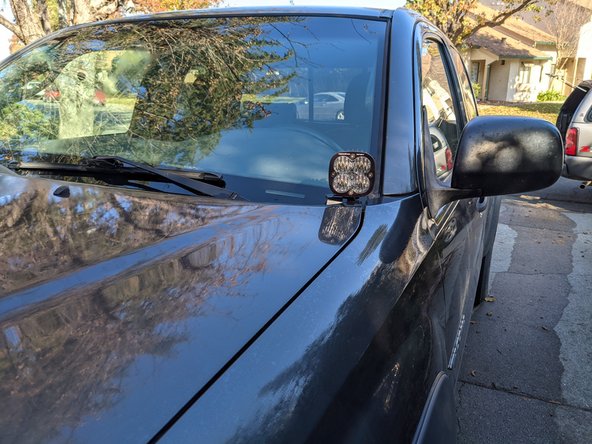 After torquing hood mounting hardware, re-install the washer hose clip.