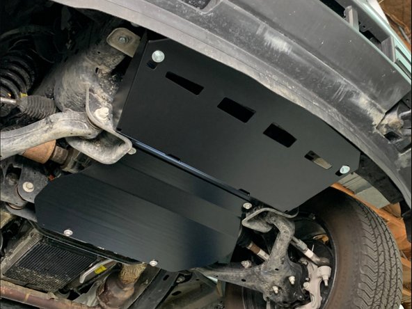 Slide the Front Engine Skid over the loosely installed hardware on the crossmember, then push it up towards the Front Engine Skid Brackets and install hardware.