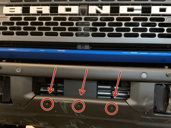 Using a T40 torx driver, remove the three bolts in the center of the bumper securing the skid plate.