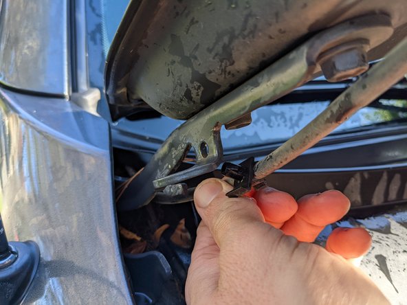 On the right side hood hinge there is a washer line clip that needs to be removed to access the bolt head. Remove this from the hinge.