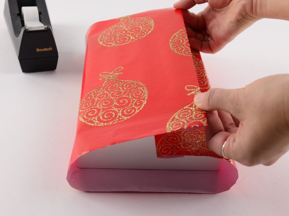 Take the just folded edge and fold it over the left side of the present.