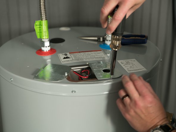 Remove the cover on the electrical junction box on the top of the water heater.
