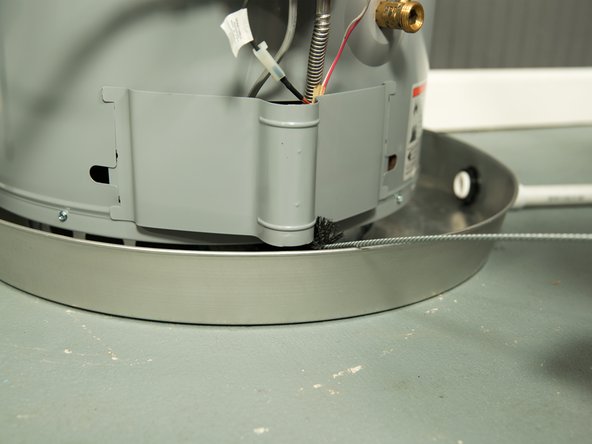 Carefully insert the brush through the openings in the bottom of the water heater.