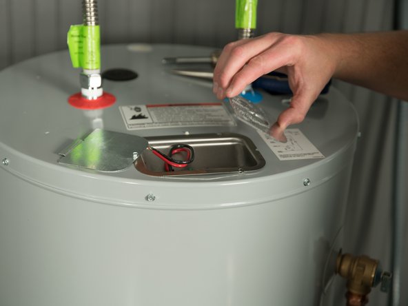 Remove the cover on the electrical junction box on the top of the water heater.
