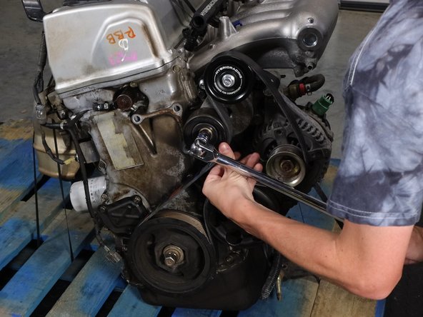 Route the belt per the diagram. Use a breaker bar or long handle wrench to move the tensioner out of the way. Slide the belt on the pulleys and release the tensioner.