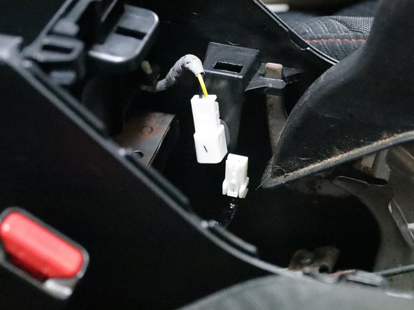 Unplug the white connector and prepare to remove the console from the car.