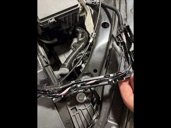 Unclip the wiring harness from its plastic guide along the front of the bay so it can be re-routed.