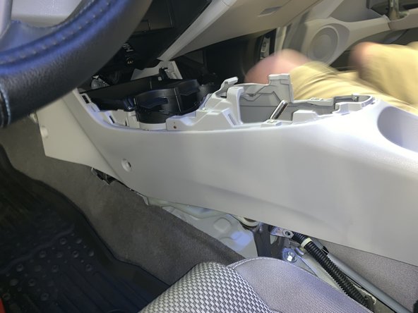 Lift the console from the rear and slide it rearward. Lift it over the shifter and remove it from the car.