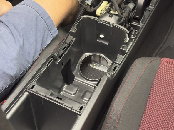 Pull upward on the cup holder section to unclip it. Remove it and set aside.