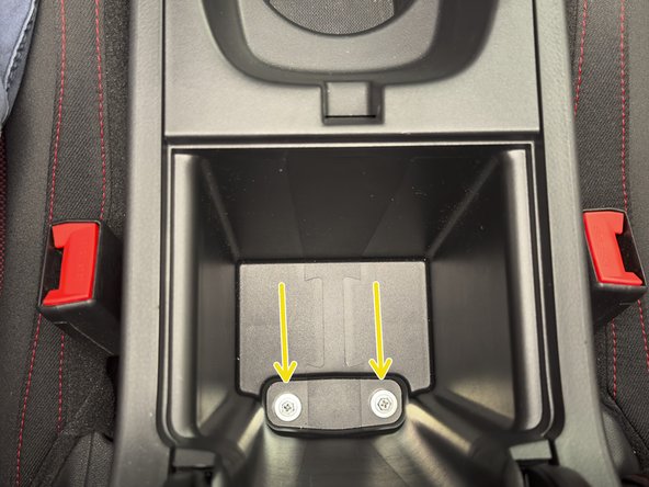 Inside of the arm rest, under the rubber cover, there are two 10mm bolts. Remove them.